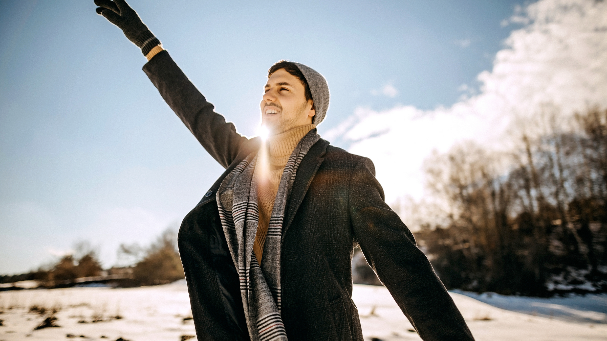 happy man in snow outdoors wearing hat, scarf and glove set