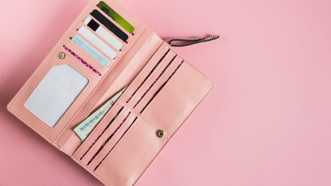 faux leather pink purse filled with cards and money on pink background