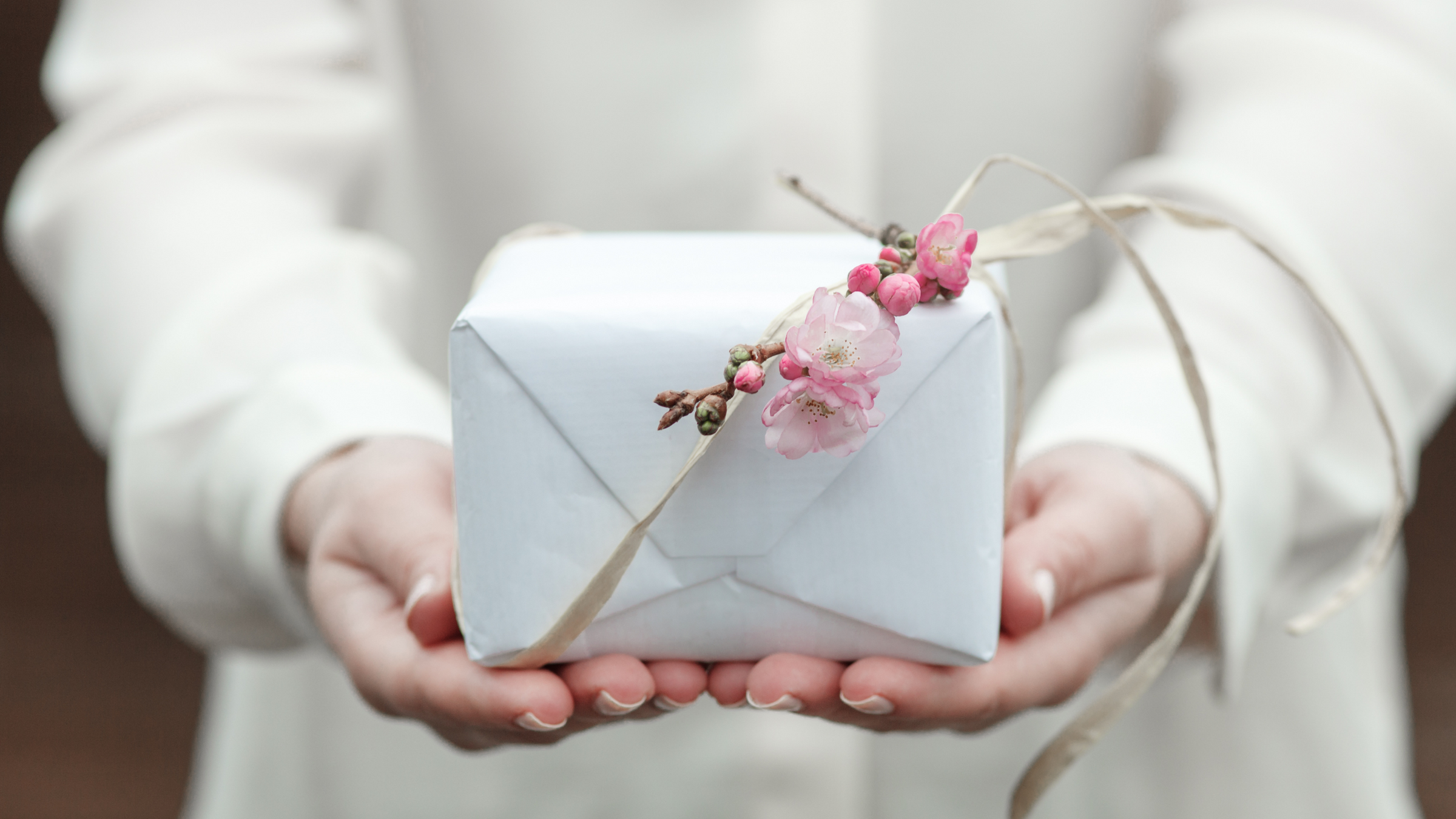 gift for mothers day wrapped in white gift wrap with pink flowers tied on top