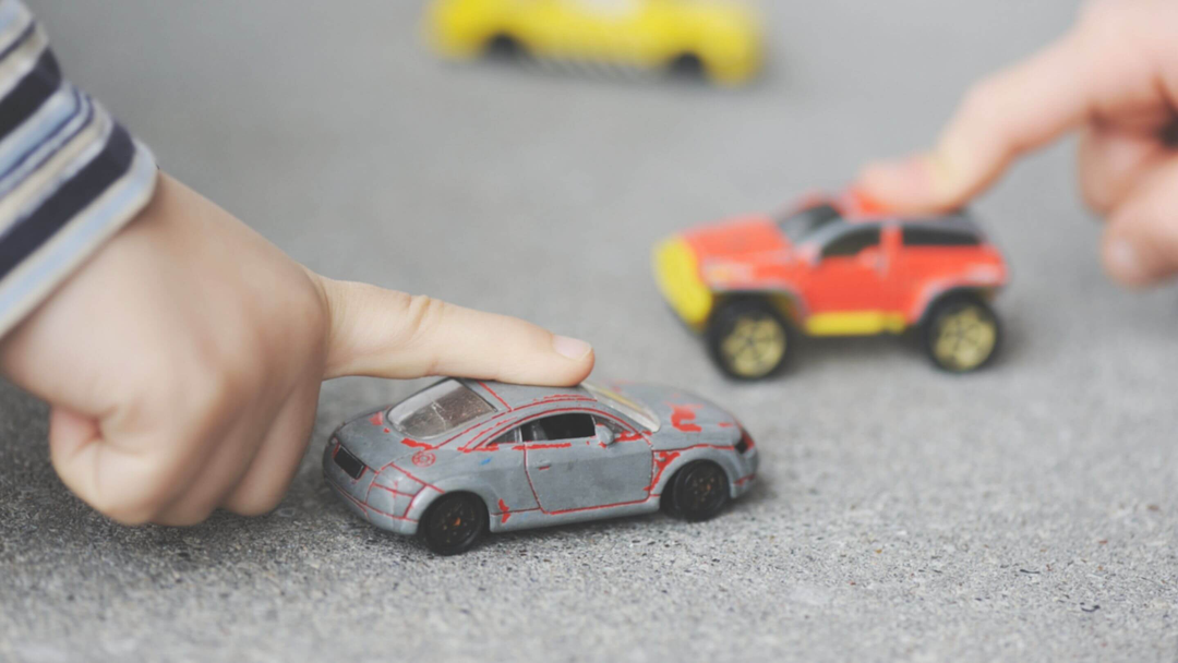 little hands pushing toy vehicles on the floor in play room