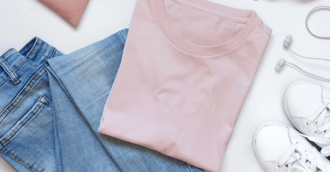 flatlay of pink t shirt, denim jeans, white training shoes and headphones on white background