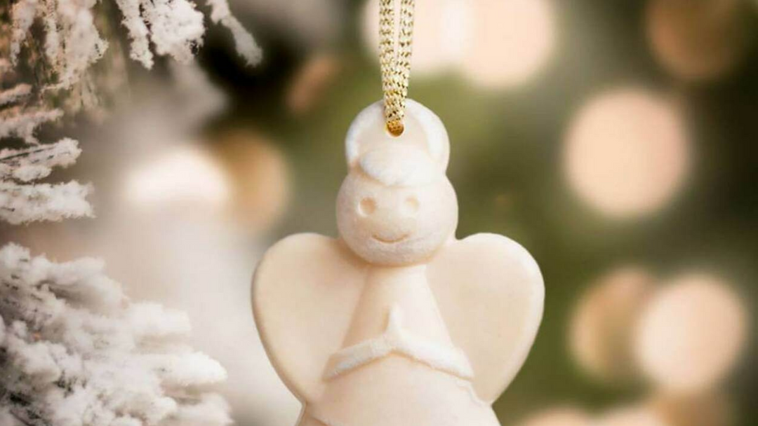 scented angel hanging from christmas tree with lights in the background