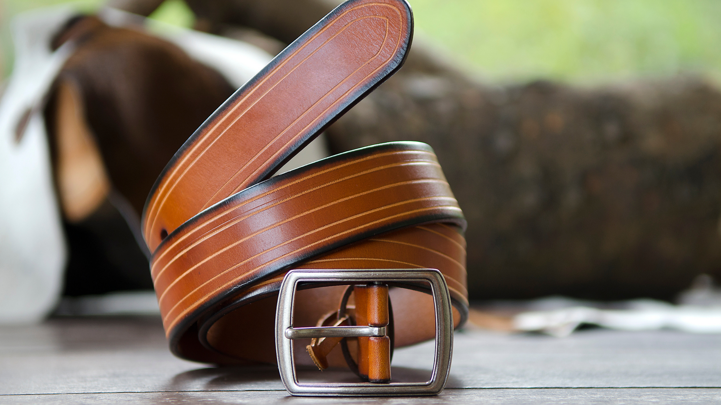 mens brown leather belt rolled up in outdoor location