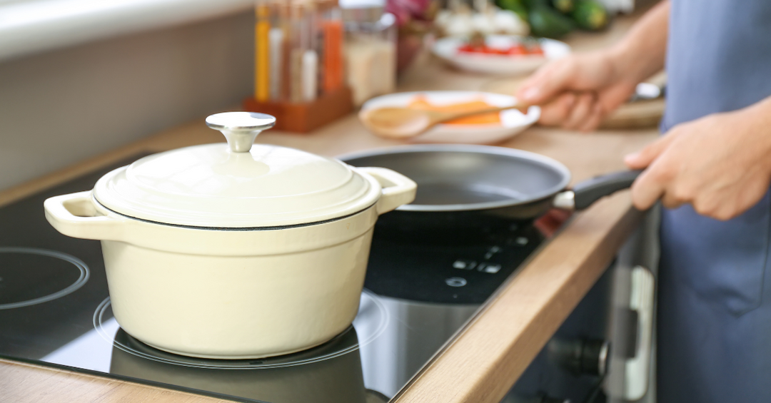 white stainless steel pot and non stick cooking pan resting on built in stove top on kitchen counter