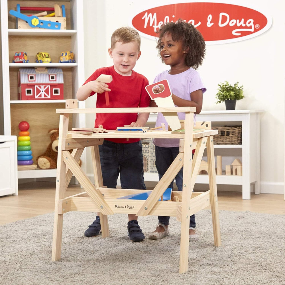 2 children playing with a wooden workbench toy with wooden tools