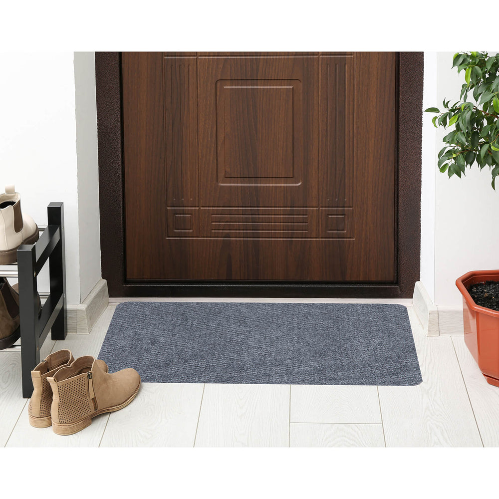 Grey door mat in front of a dark wood door with planter and boot rack