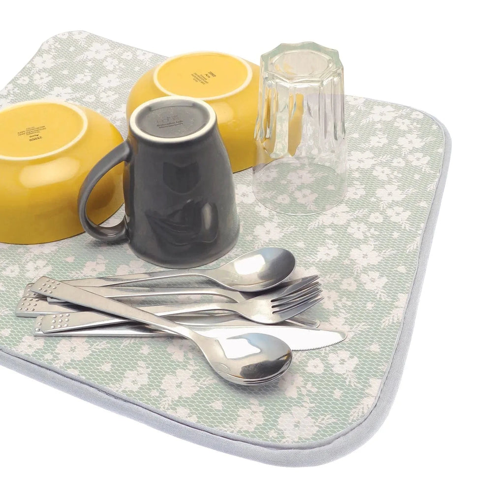 Green floral draining mat with cutlery, glass, mug and bowls on it