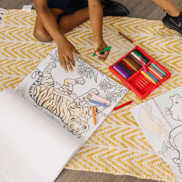 young boy ses chalk pencils to colour in tiger outline on floor in living room