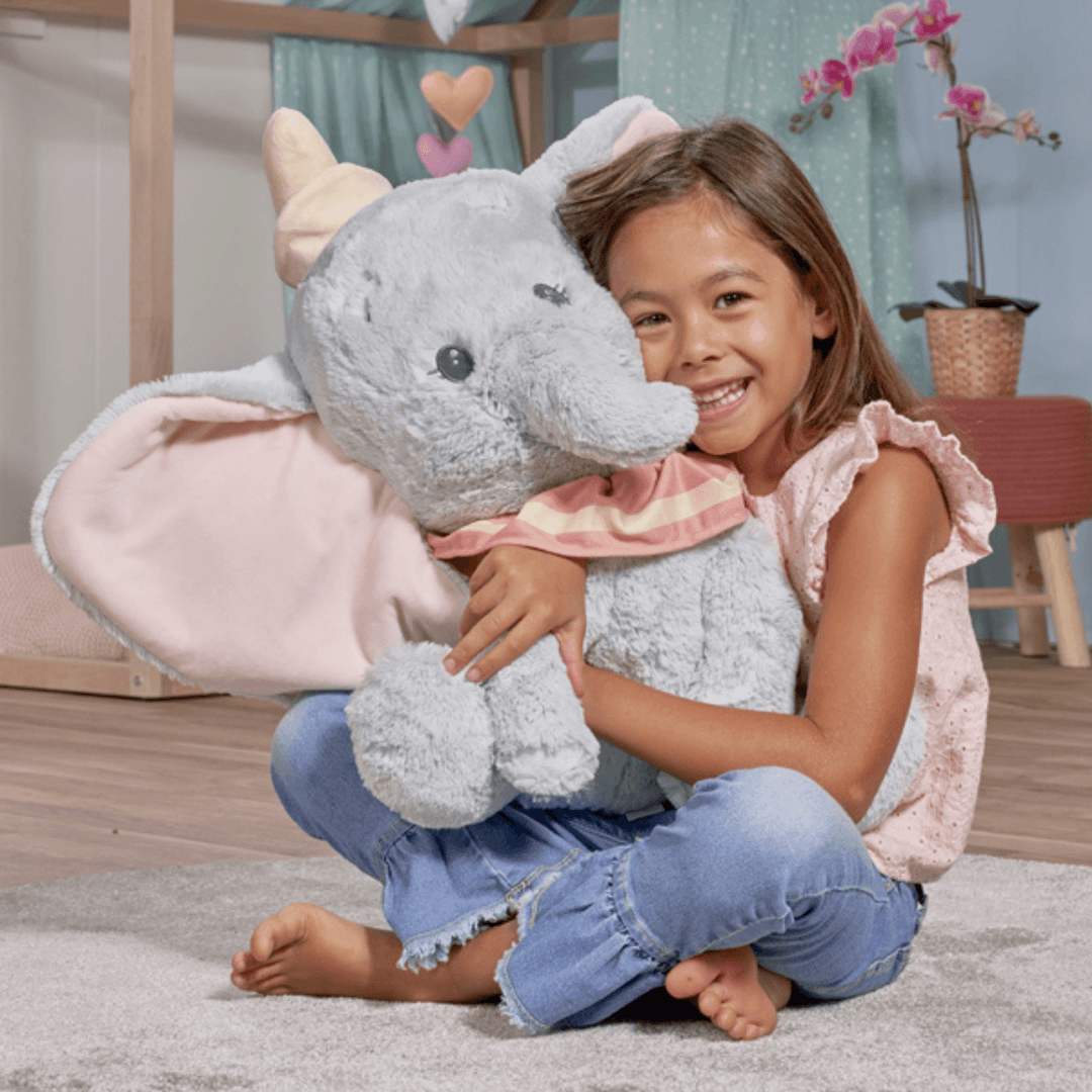 little girl in bedroom hugging large dumbo plush toy