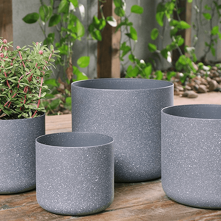 set of 4 light grey planters in outdoor patio space with foliage in the background