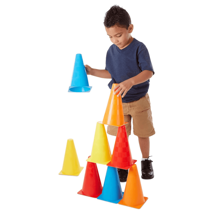 young boy places orange cone on top of colourful cone tower