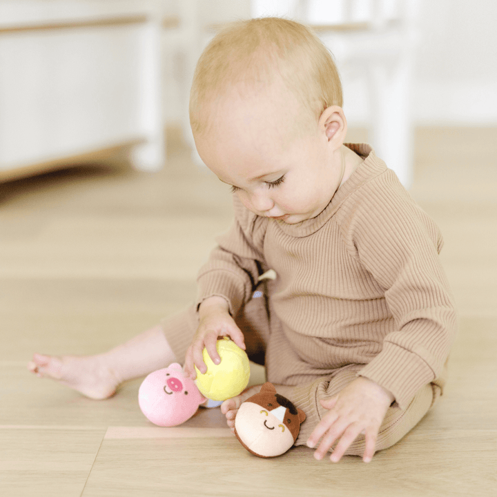 toddler plays with 3 of 4 farm friends on wooden floor