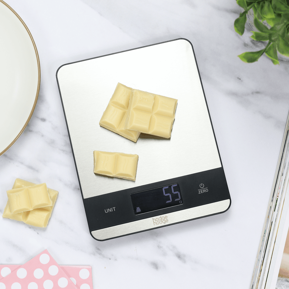 slim electronic kitchen scales on marble worktop weighing white chocolate blocks