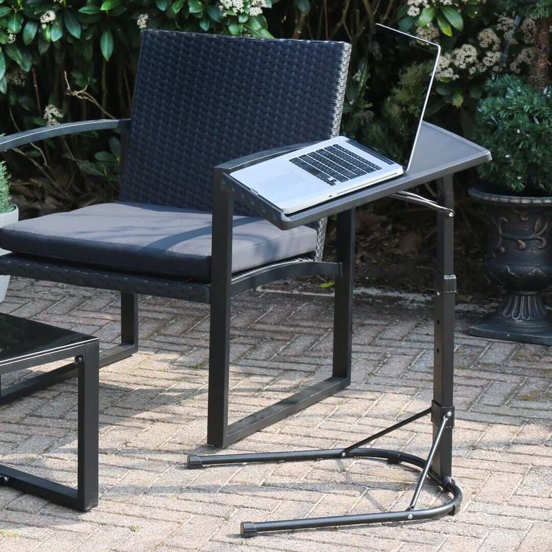 laptoop table on outdoor patio space beside rattan furniture set with laptop resting on top