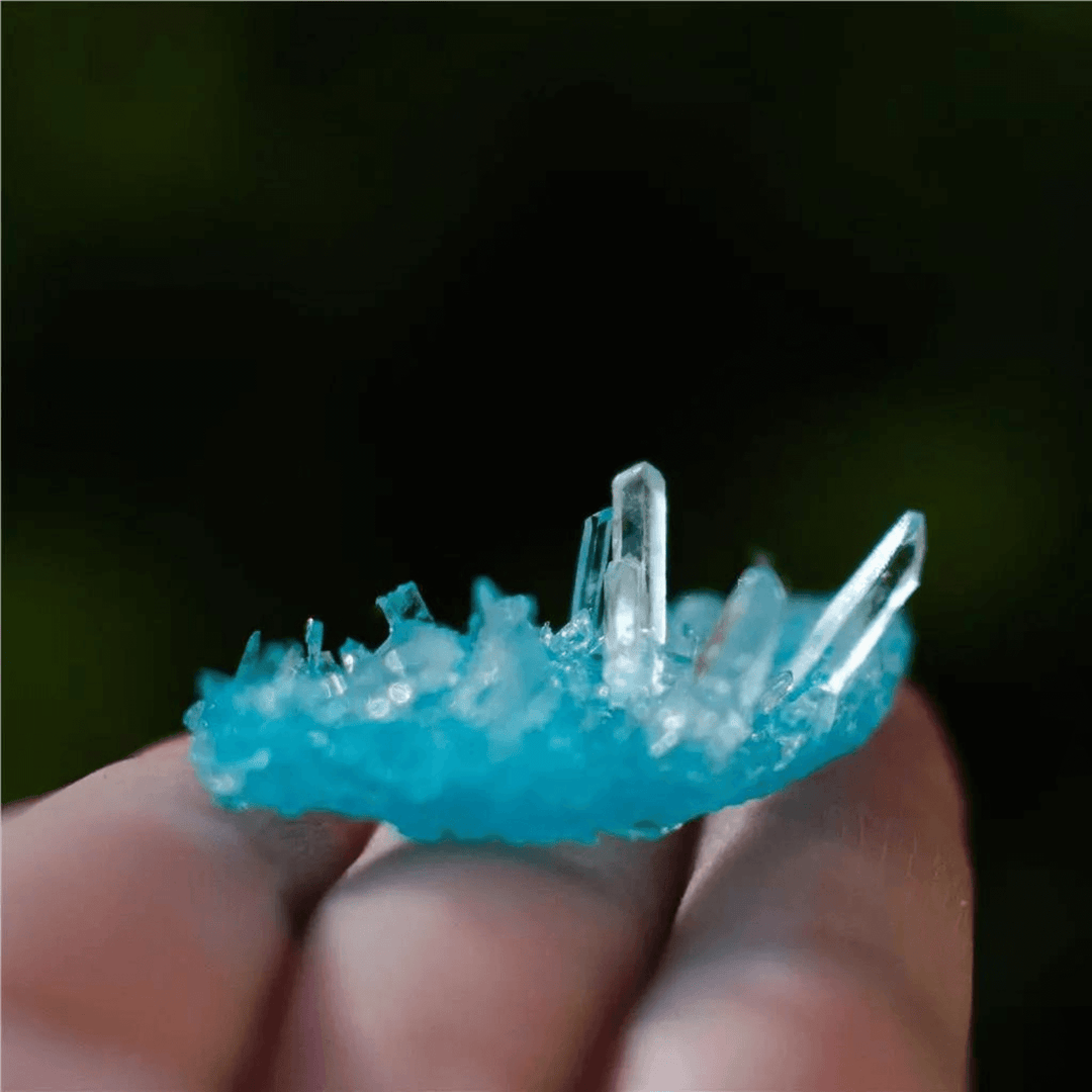 blue colour sparkling crystal resting on the edge of someones hand