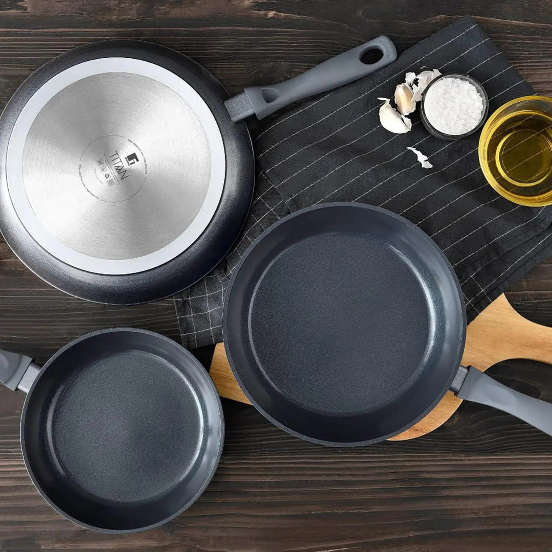 Top view of wooden bench with black non-stick frying pans and chef's apron