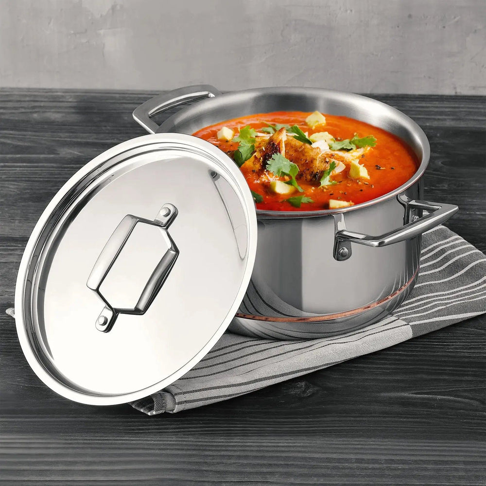 Polished stainless steel soup pot with lid aside to show a chicken ragout meal