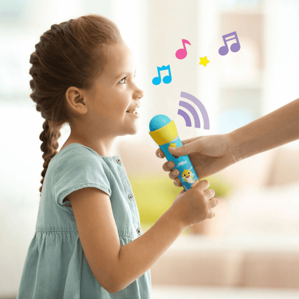 little girl singing into baby shark microphone at home with Mum