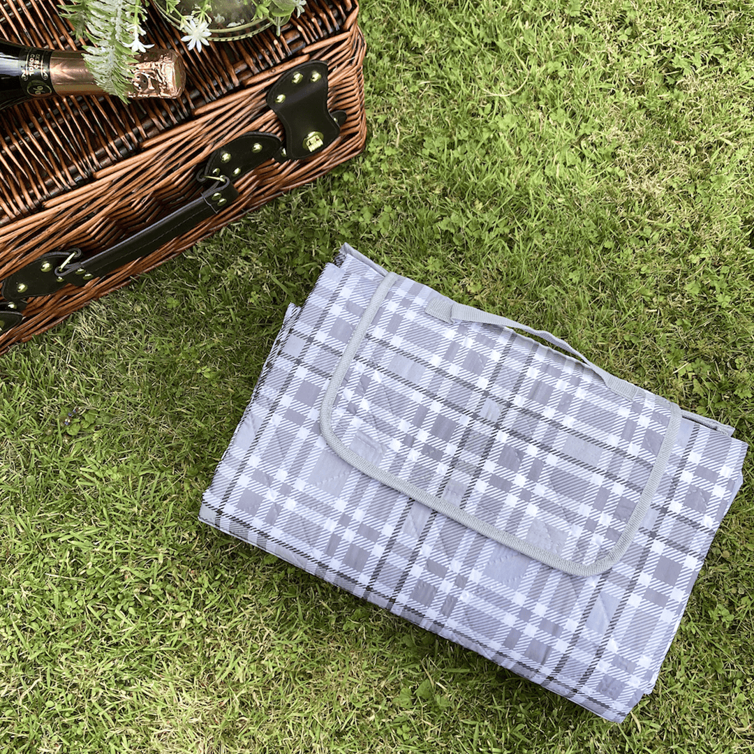 grey picnic blanket on grass area beside wicker picnic basket