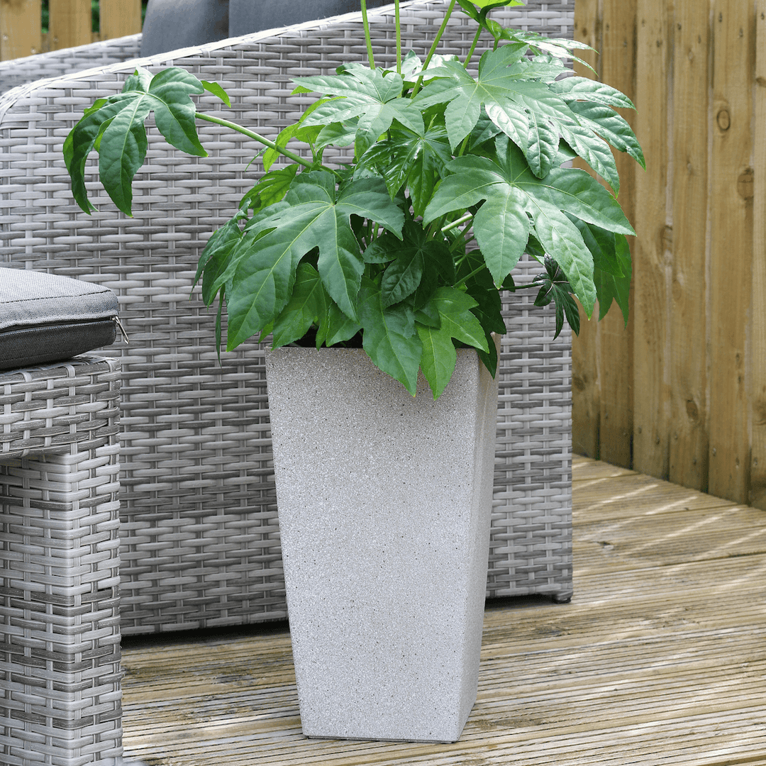 tall grey sandstone style planter on patio space in front of rattan furniture with green plant