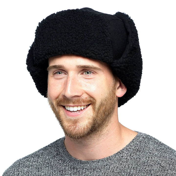 man wearing a black fleece trapper hat with long ear flaps fastened on top of the winter hat