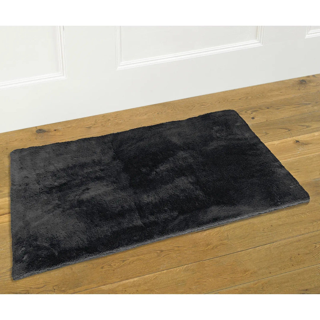 Rectangular grey faux fur rug on a wooden floor and white panelled wall