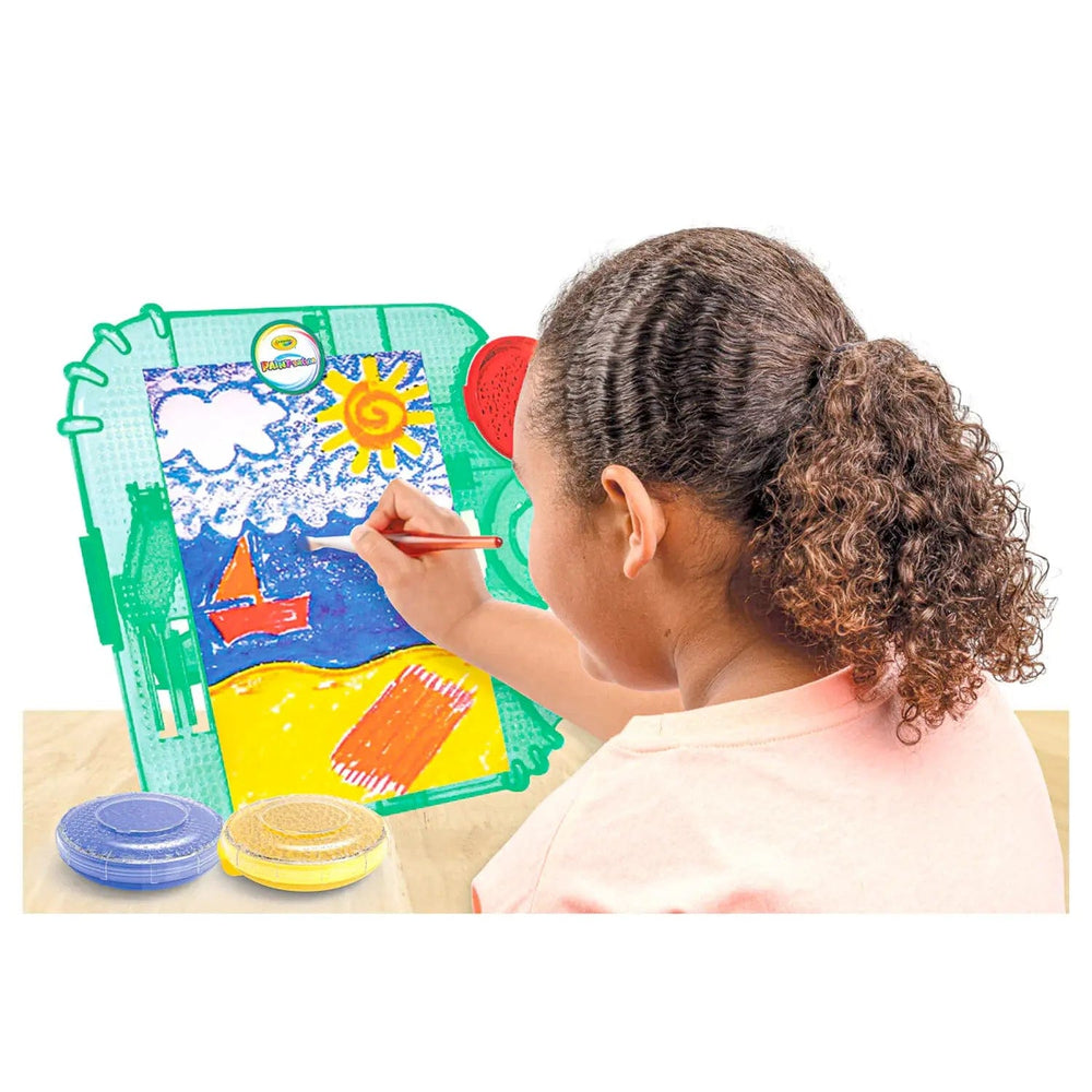 Child sitting at a Crayola table top easel with 3 paint pods and paint brush