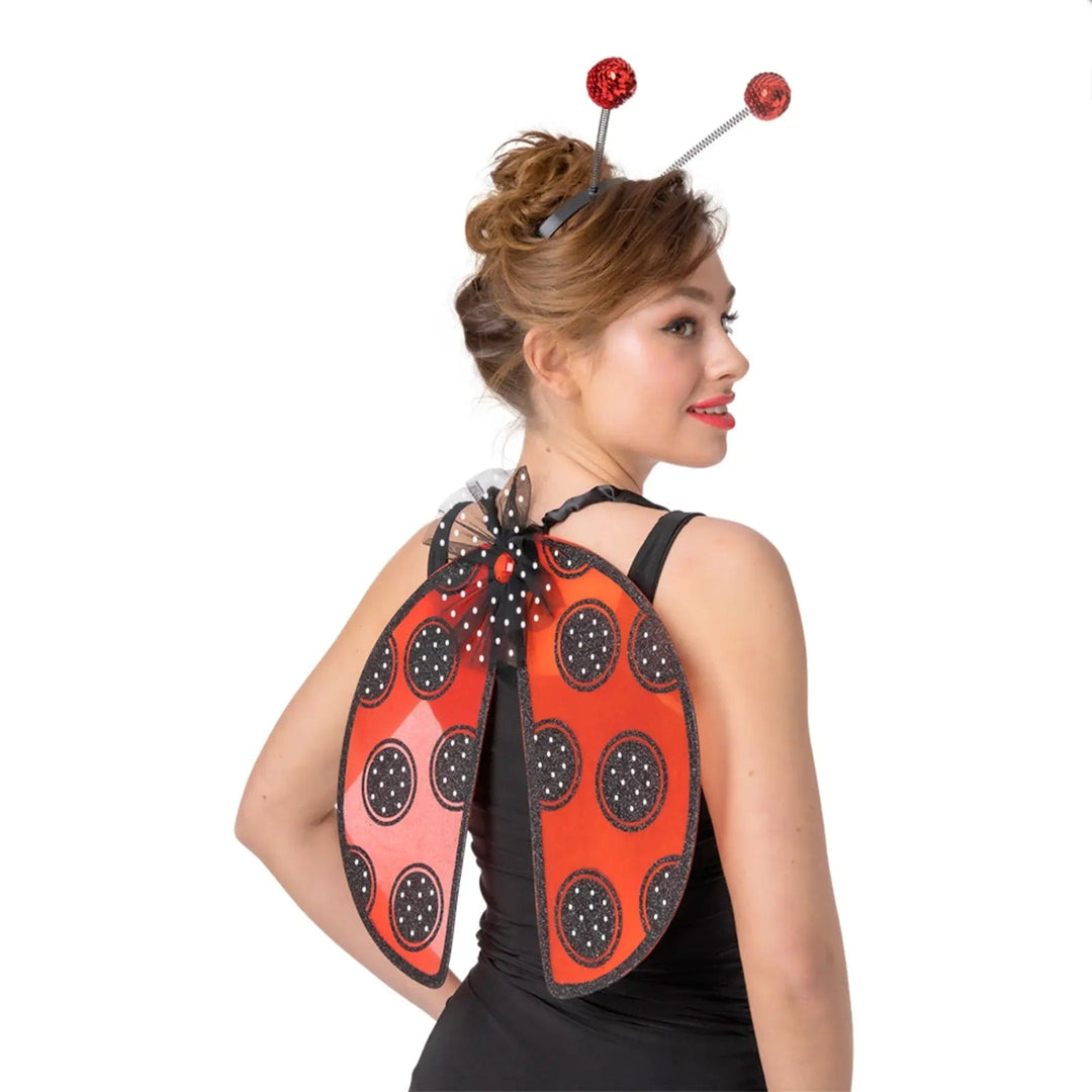 Lady wearing a pair of ladybird wings in red with black spots and a set of red sequin head boppers for fancy dress costumes