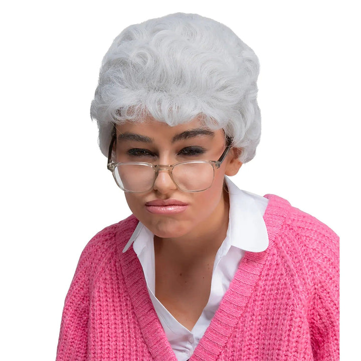 Woman scowling wearing an old lady grey wig, glasses and a pink cardigan for fancy dress costumes