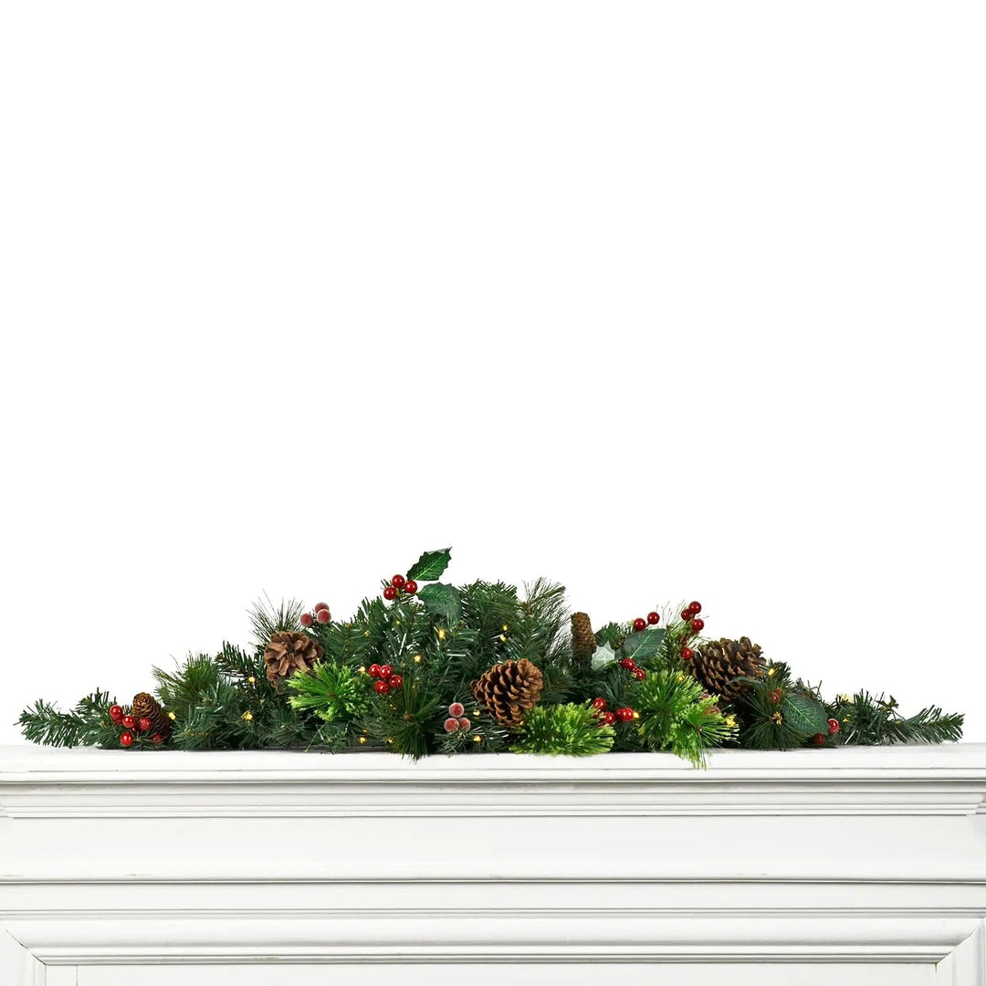 a 90cm long light up Christmas swag decoration with green pine foliage and red berries draped along a fireplace mantelpiece