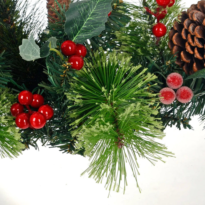 Close up of green pine branches, holly berries and leaves, frosted red berries and pine cones