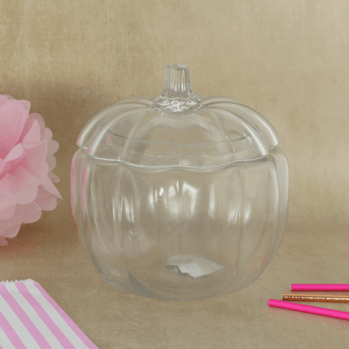 glass pumpkin storage container on beige coloured background with pink and rose gold straws in the front