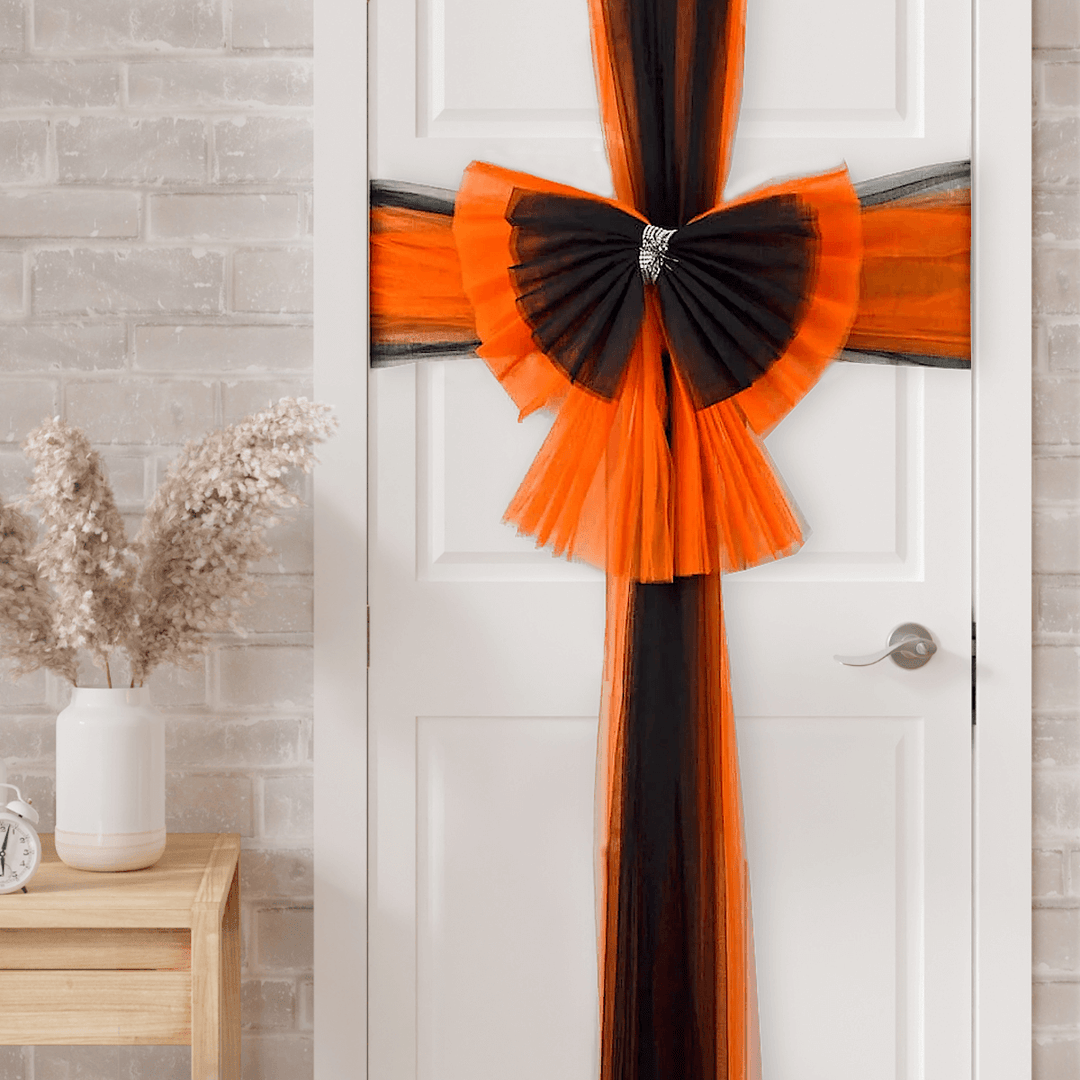 halloween door bow on white door beside console table with dried flowers
