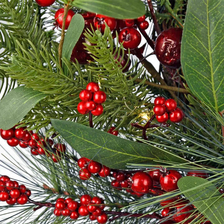 close up of red berries and green pine branches on a light up christmas wreath