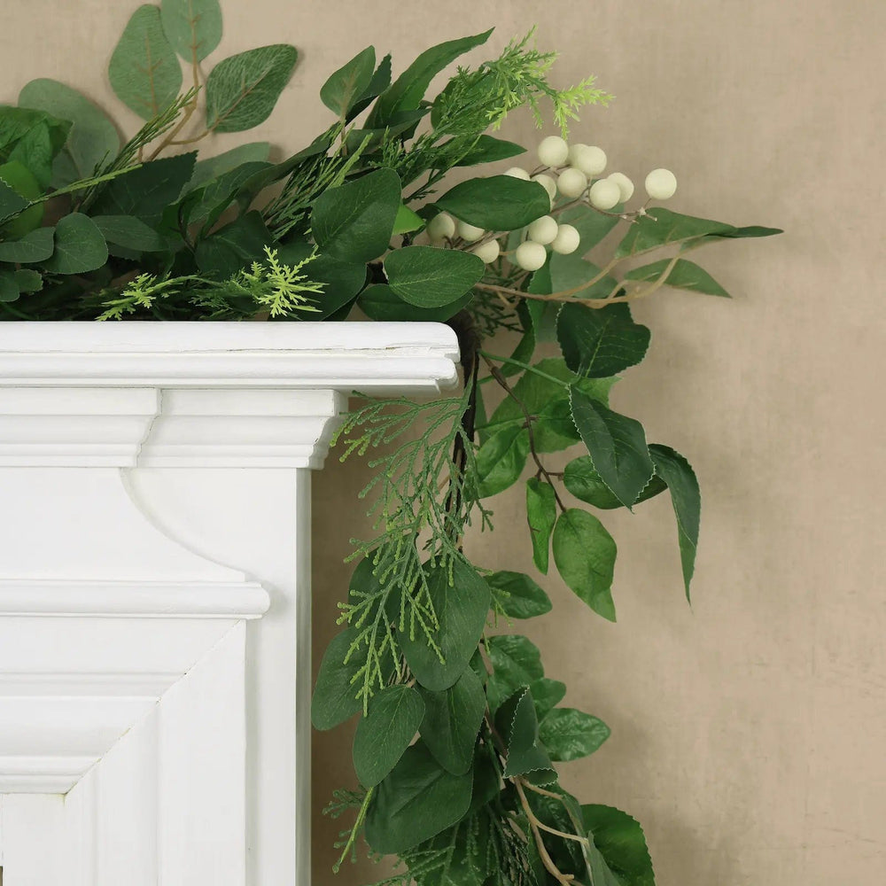 Woodland green Christmas garland with white berries trialing over a mantelpiece