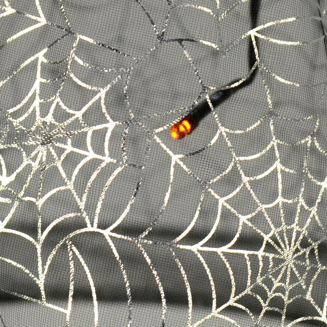 Close up of an orange LED light inside silver spder web pattern witch hat hanging light