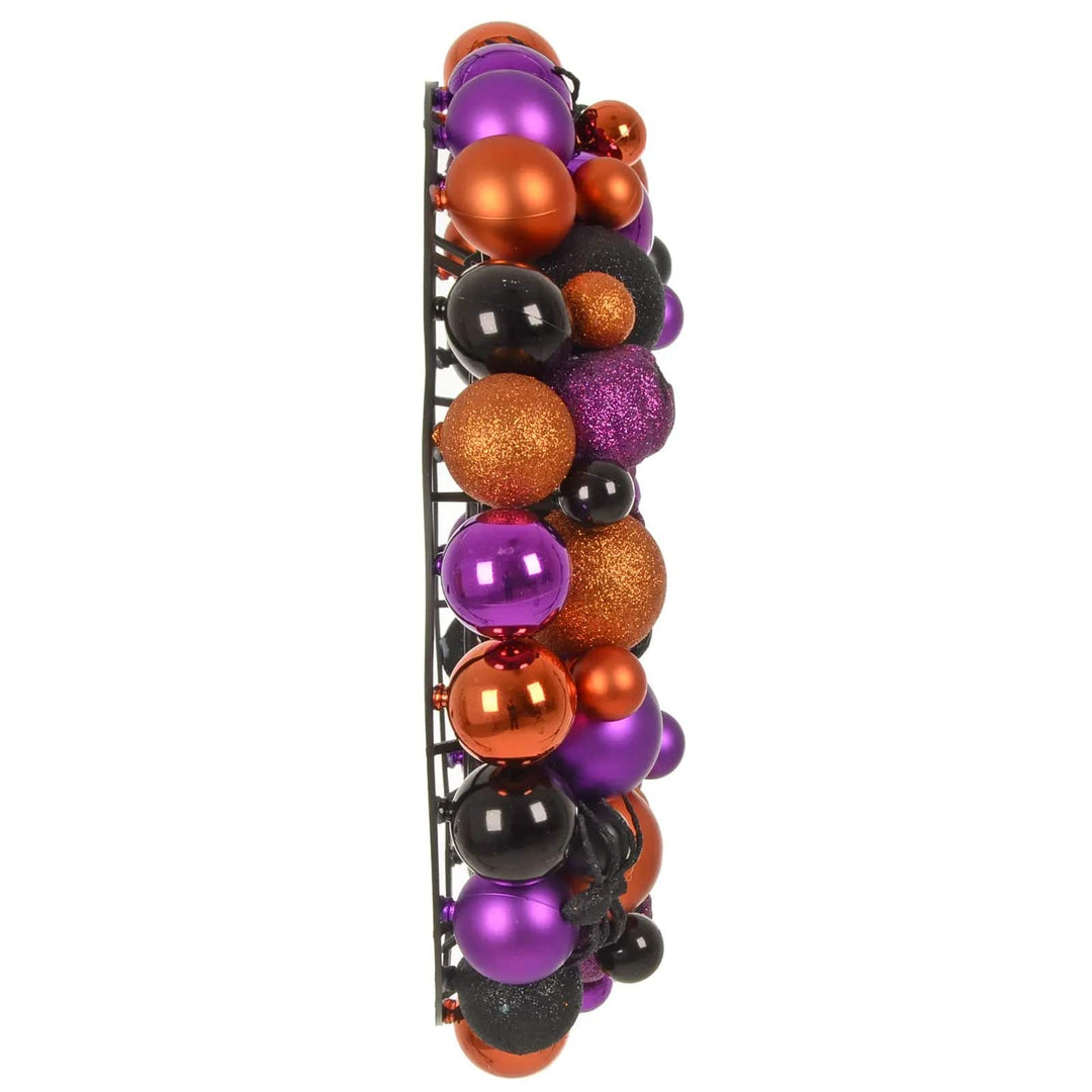 Side view of a Halloween wreath with orange, purple and black baubles