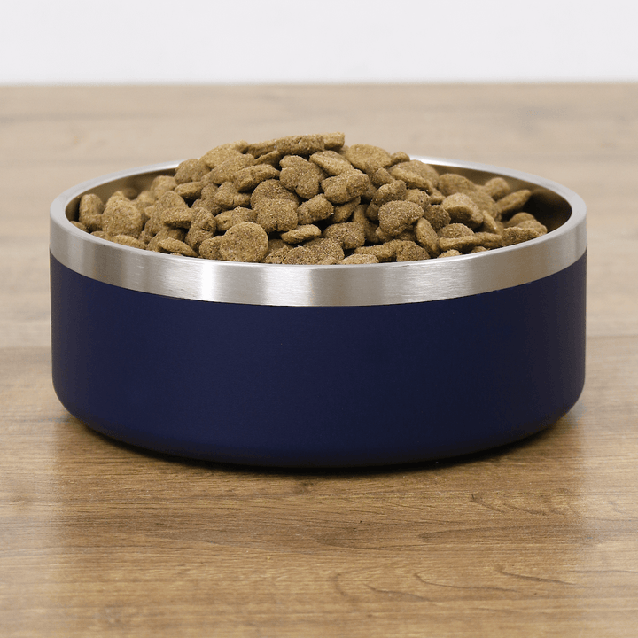 front view of dog bowl filled with dog biscuits on wooden floor