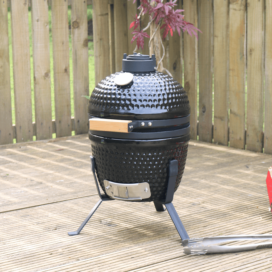 kamado egg bb on patio space beside bbq food utensils with red tree in background