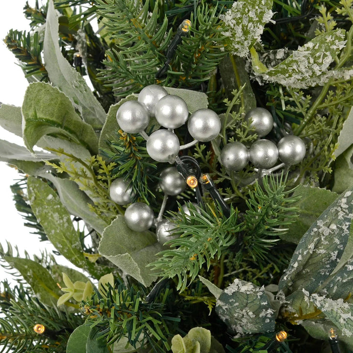 Close up of LED lights, frosted green leaves and silver berries on a Christmas tree