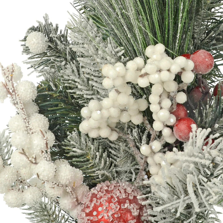 Snowberries, red baubles and snow flocked pine branches on a Christmas garland