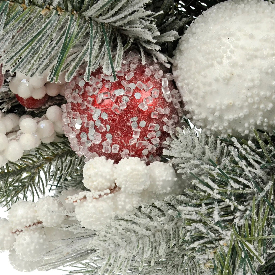 White snowy bauble and red frosted Christmas bauble, snowberries and green frosted pine branches