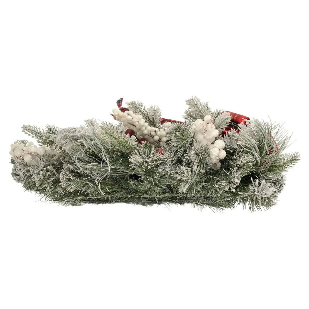 Side view of a Christmas garland with frosted branches, red tartan and snowberries