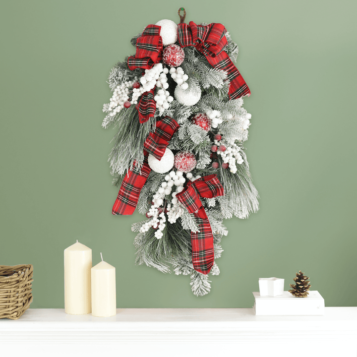 red and white christmas swag decoration on green wall above fireplace mantel